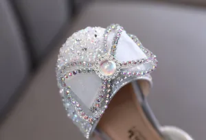 Close-up of sparkling rhinestones and white mesh bow on elegant girls' princess party shoes