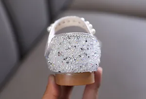 Macro detail of girls princess shoes featuring white pearls and sparkling rhinestone heel