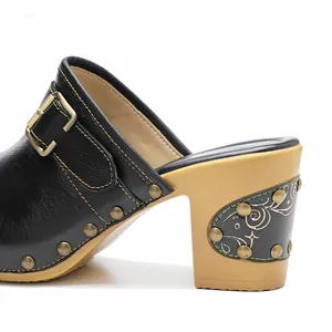 Détail d'une mule rétro en cuir noir avec rivets et talon bloc décoratif sculpté
