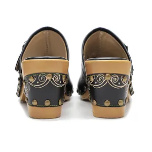 Vue détaillée de sabots en cuir noir vintage avec talons carrés décorés et clous.