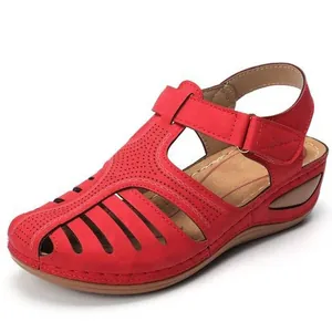 Detalle de sandalias rojas con cuña y diseño calado con cierre de velcro ajustable.