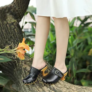 Sabots rétro en cuir noir faits main avec talons épais dans un décor de jardin naturel