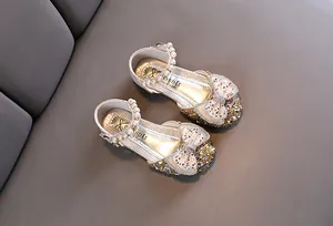 Detailed view of silver girls princess shoes with sparkling bows and pearl straps.