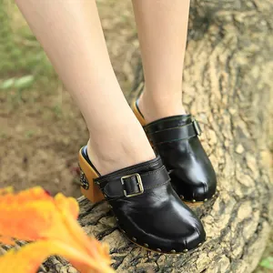 Vue détaillée de sabots vintage en cuir noir avec boucle sur un tronc d'arbre.