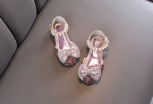 Detailed view of pink sparkly girls' princess shoes with bow-knot and pearl strap