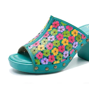 Gros plan de sandales vintage en cuir sarcelle avec des motifs floraux colorés