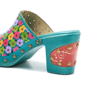 Gros plan de mules vintage en cuir peintes à la main avec fleurs et talons épais.