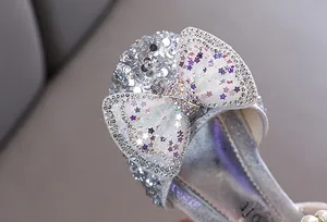 Macro detail of a silver sparkling bow with rhinestones and star sequins on girl's flat