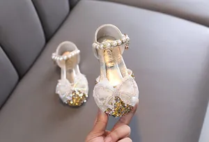 Nahaufnahme funkelnder goldener Prinzessinnenschuhe für Mädchen mit Paillettenschleife.