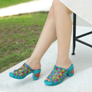 Gros plan de sandales à talons épais en cuir à fleurs turquoise portées à l'extérieur