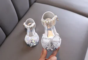 Nahaufnahme von glitzernden Mädchen-Prinzessin-Schuhen mit Perlenriemen und Schleife