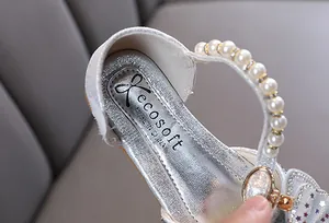 Close-up of silver girl's princess shoe with pearl strap and rhinestone bow detail.