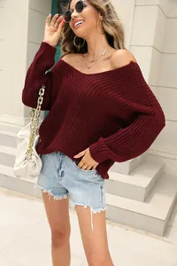 Detailed view of women's burgundy V-neck knit sweater in an outdoor street style setting