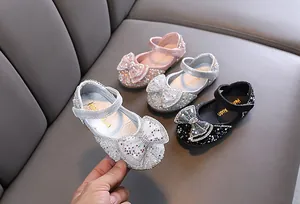 Dettaglio di scarpe da principessa scintillanti per bambine con grande fiocco e paillettes