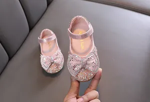 Dettaglio di scarpe da principessa rosa glitterate per bambine con fiocco di strass