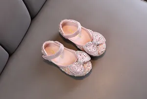 Dettaglio di scarpe da principessa rosa con paillettes per bambina e fiocco glitter.