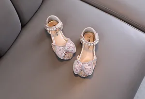 Nahaufnahme von rosa Prinzessinnenschuhen für Mädchen mit Glitzerschleife und Perlenriemen