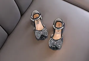 Detailansicht von funkelnder Strass-Schleife und eleganten Perlen auf Mädchen-Schuhen