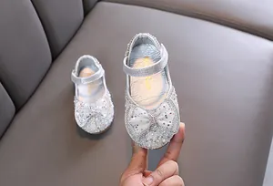 Primo piano dei brillantini argentati e del fiocco sulle scarpe da ballo della principessa