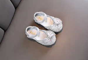 Primo piano di scarpe da principessa argento glitterate per bambina con fiocco e velcro