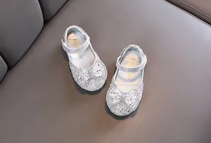 Dettaglio di scarpe da principessa argento per bambine con paillettes e fiocco lucido