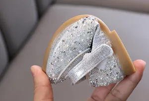 Dettaglio scarpe da principessa argento con suola morbida per bambina e perle strass.