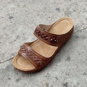 Detail of brown women's wedge sandal with elegant embroidery and white stitching