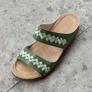 Detailed top view of green embroidered wedge sandals with intricate woven straps