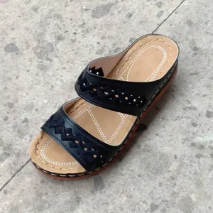 Detail shot of black wedge sandals with decorative cut-outs and white stitching
