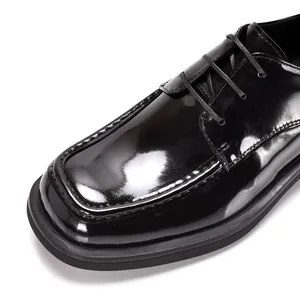 Detailansicht von glänzenden schwarzen Lacklederschuhen mit eckiger Zehenpartie und Naht