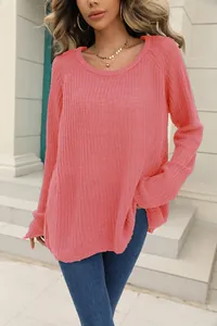 Close-up of coral pink knit sweater with detailed texture and relaxed fit