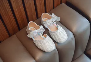 Detailaufnahme der silbernen Prinzessinnenschuhe für Mädchen mit Perlen- und Schleifenverzierung