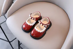 Close-up of red patent leather girl's Mary Jane shoes with pearl strap and lace trim