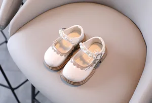 Detailed view of white patent leather Mary Jane shoes for girls with pearl strap