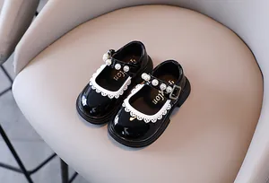 Detail view of girls black patent leather Mary Jane shoes with pearl straps and lace trim