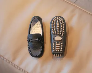 Detail view of black children's loafers showing textured leather and rubber stud sole.