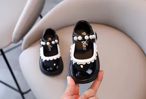 Detailed view of girls black patent leather Mary Jane shoes with pearl and lace trim