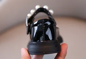 Close-up of black patent leather girls' princess shoes featuring pearl heel accents