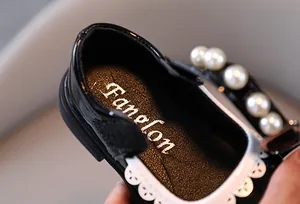 Detail shot of black patent leather girl's dress shoe featuring pearls and lace