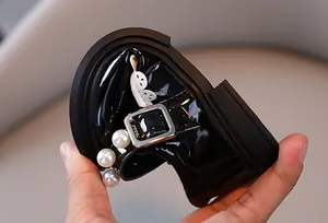 Detail showing the flexibility of black patent leather girls shoes with pearls.