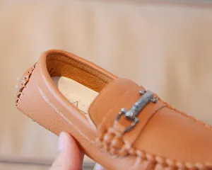 Close-up of boys' brown leather loafers showing pebbled texture and metal buckle