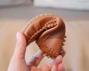 Detailed macro shot showing the extreme soft flexibility of brown leather toddler loafers