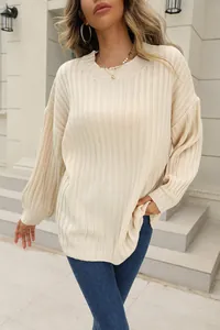 Vue détaillée d'un pull beige en maille côtelée porté par un mannequin en extérieur