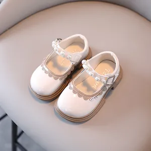 White patent leather toddler Mary Jane shoes with pearl straps and scalloped trim