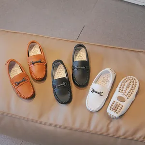 Boys vintage leather loafers in black brown and white displayed on tan background