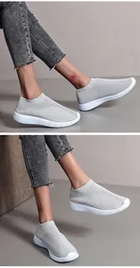 Detail view of stylish grey flyknit breathable slip-on sneakers worn with denim jeans.