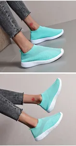 Mint green fly-knit breathable slip-on sneakers with white grooved soles shown on model.
