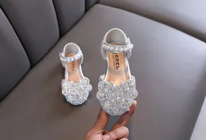 Close-up of silver girls princess shoes with butterfly rhinestone and pearl strap
