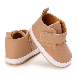 Detailed view of brown infant walking shoes with white soft soles and velcro strap.