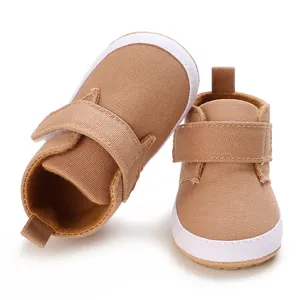 Detail view of tan canvas infant walking shoes with white soft soles and velcro strap